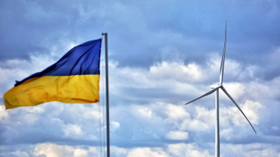 ukraine flag flying next to wind turbine in front of blue sky with clouds